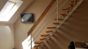 a living room with stairs with a tv on the wall at Végvár Delux apartman in Gyula