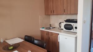 a small kitchen with a table and a microwave at Végvár Delux apartman in Gyula