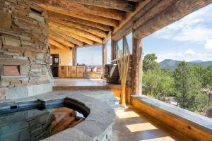 Earthship retreat + 2 spas + incredible views. في سانتا فيه: مسبح خارجي في مبنى حجري مع نافذة كبيرة