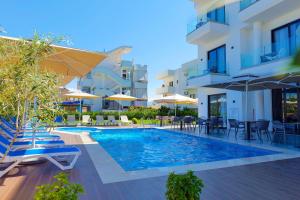 een zwembad met stoelen en parasols naast een gebouw bij Hotel Alexander in Ksamil