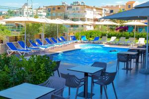 een zwembad met tafels, stoelen en parasols bij Hotel Alexander in Ksamil