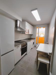 een keuken met witte kasten en een tafel. bij Apartamento Santander Maliaño in Maliaño