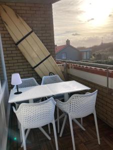 d'une table et de chaises blanches sur un balcon. dans l'établissement CallantsDuinzicht, Beachappartement 24, à Callantsoog