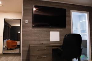 a room with a desk with a chair and a television on a wall at Glengarry Extended Stays in Truro