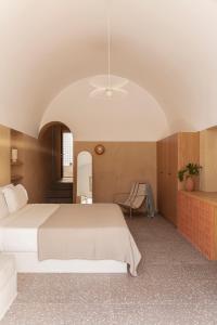 a bedroom with a white bed and a chair at Ethos Vegan Suites in Fira