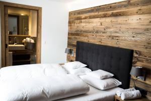 um quarto com uma cama branca e uma parede de madeira em der grüne Baum Mountain Boutique Hotel em Ehrwald