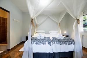 een slaapkamer met een wit hemelbed met witte kussens bij Shoestrings Backpackers Lodge Vic Falls in Victoria Falls