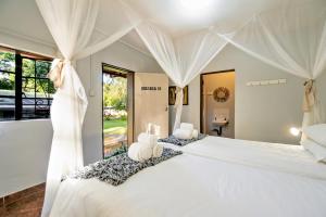 een slaapkamer met een groot bed met witte gordijnen bij Shoestrings Backpackers Lodge Vic Falls in Victoria Falls