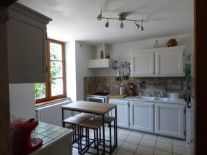 een keuken met witte kasten en een houten tafel bij MAISON SYLVAIN in Tournus