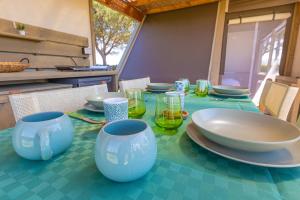 a table with plates and bowls and glasses on it at Glamping Gli Etruschi in Piombino