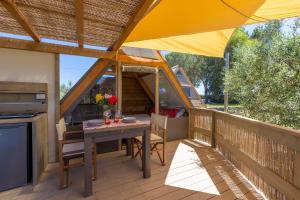 a patio with a table and a yellow umbrella at Glamping Gli Etruschi in Piombino