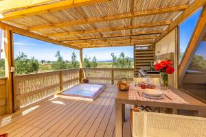 a deck with a table and a swimming pool at Glamping Gli Etruschi in Piombino