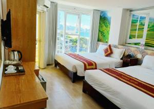 una camera d'albergo con due letti e una grande finestra di VANDA Hotel Nha Trang a Nha Trang