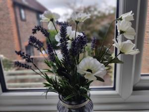 un vase rempli de fleurs blanches et violettes dans une fenêtre dans l'établissement Frankland - Emsworth Harbour 3 Bedroom House, à Emsworth