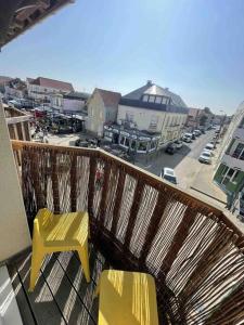 - un balcon avec deux chaises jaunes et une rue dans l'établissement Appart Marion vue mer avec Wifi sur Quend plage, à Quend