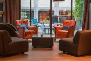 a living room with chairs and a table and a room withwindows at Hotel Neuvice in Liège