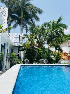 a swimming pool in front of a house with palm trees at The Quetzal in Cancún