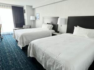 two beds in a hotel room with white sheets at Chelsea Hotel Toronto in Toronto