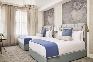 two beds in a hotel room with blue and white at The Wall Street Hotel New York City in New York