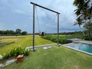 a person on a swing in a garden with a pool at The Valerian Villa Ubud in Ubud