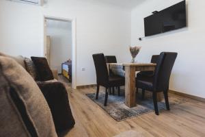 - une salle à manger avec une table, des chaises et un canapé dans l'établissement ALFA Apartmani, à Subotica