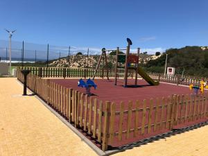 un parco giochi con scivolo in cima a un tappeto rosso di São Torpes by Campigir a Sines