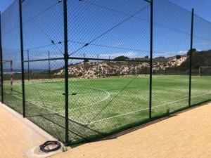 una gabbia di battuta con un campo da calcio dietro. di São Torpes by Campigir a Sines