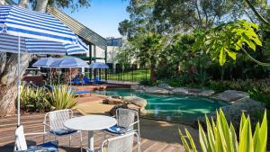 a pool with a table and chairs and an umbrella at Eden Oak Geelong in Geelong