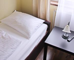 uma cama com lençóis brancos e uma mesa lateral com um candeeiro em Hotel Hoffinger em Viena