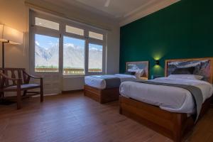 a bedroom with two beds and a green wall at LOKAL x Skardu (City Center) in Skardu