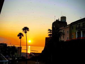 un coucher de soleil sur l'océan avec des palmiers et un bâtiment dans l'établissement Azzurro come il Mare, à Termoli