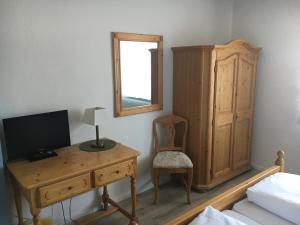 um quarto com uma secretária, uma televisão e um espelho. em Hotel und Restaurant -Gasthaus Zur Pfalz em Hockenheim