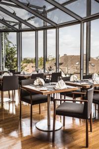 een eetkamer met tafels, stoelen en ramen bij Hotel Ambassador in Bern