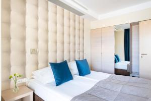 - une chambre avec un grand lit blanc et des oreillers bleus dans l'établissement Hotel Arkon Park Gdańsk- Destigo Hotels, à Gdańsk