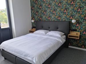 een slaapkamer met een groot bed met bloemenbehang bij BED Cauchy in Namen