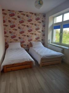 Dos camas en una habitación con una pared con coches. en Apartament ZOSIA, en Korczyna