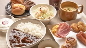 una mesa con platos de comida y una taza de café en Via Inn Shin Osaka, en Osaka