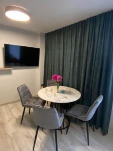 a table with chairs and a vase of flowers on it at ADI Apartamentai in Panevėžys