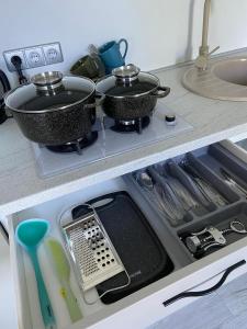 two pots and pans on a stove in a kitchen at ADI Apartamentai in Panevėžys