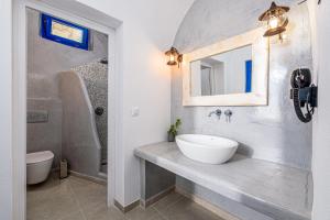 bagno con lavandino, servizi igienici e specchio di Anatoli Hotel & Spa a Firà