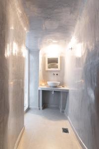 bagno con lavandino bianco e specchio di Anatoli Hotel & Spa a Firà