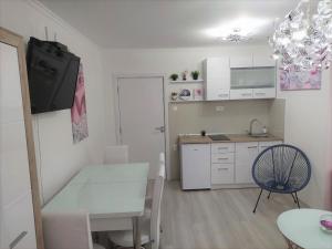 una pequeña cocina blanca con mesa y silla en City Lux Apartments, en Skopje