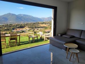 uma sala de estar com um sofá e uma grande janela em Appartement neuf 3 chambres vue mer Propriano em Propriano