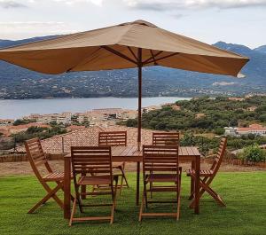 uma mesa de madeira com cadeiras e um guarda-sol em Appartement neuf 3 chambres vue mer Propriano em Propriano