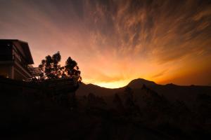 un tramonto su una montagna con il sole nel cielo di Chandys Drizzle Drops - Munnar Top Station a Munnar