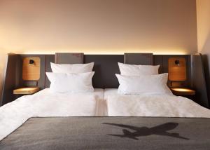 a bedroom with two beds with white sheets and pillows at ATLANTIC Hotel Airport in Bremen