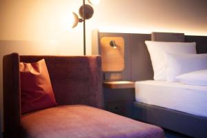 a bedroom with a bed and a chair with a pillow at ATLANTIC Hotel Airport in Bremen