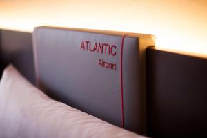 a book with the wordsatlantic approach sitting on a bed at ATLANTIC Hotel Airport in Bremen