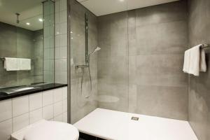 a bathroom with a shower with a toilet and a sink at ATLANTIC Hotel Airport in Bremen