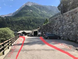 un coche aparcado en un aparcamiento junto a una pared de piedra en Affittacamere Buenavista Guest House, en Champoluc